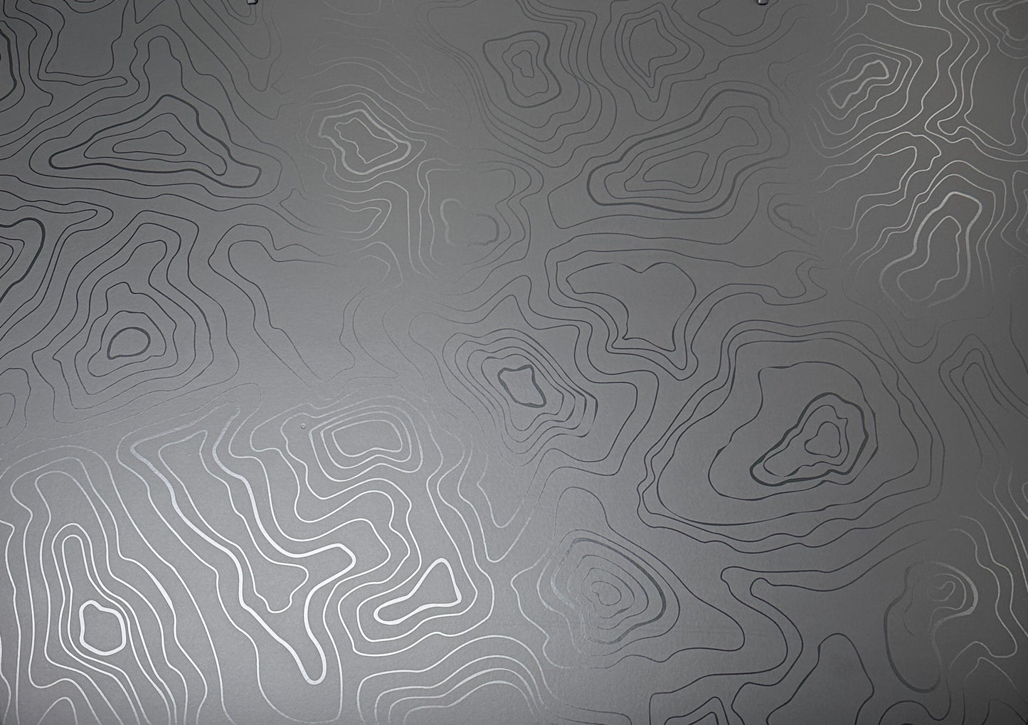 Matte black background with satin black topo lines that show up in the sunlight.